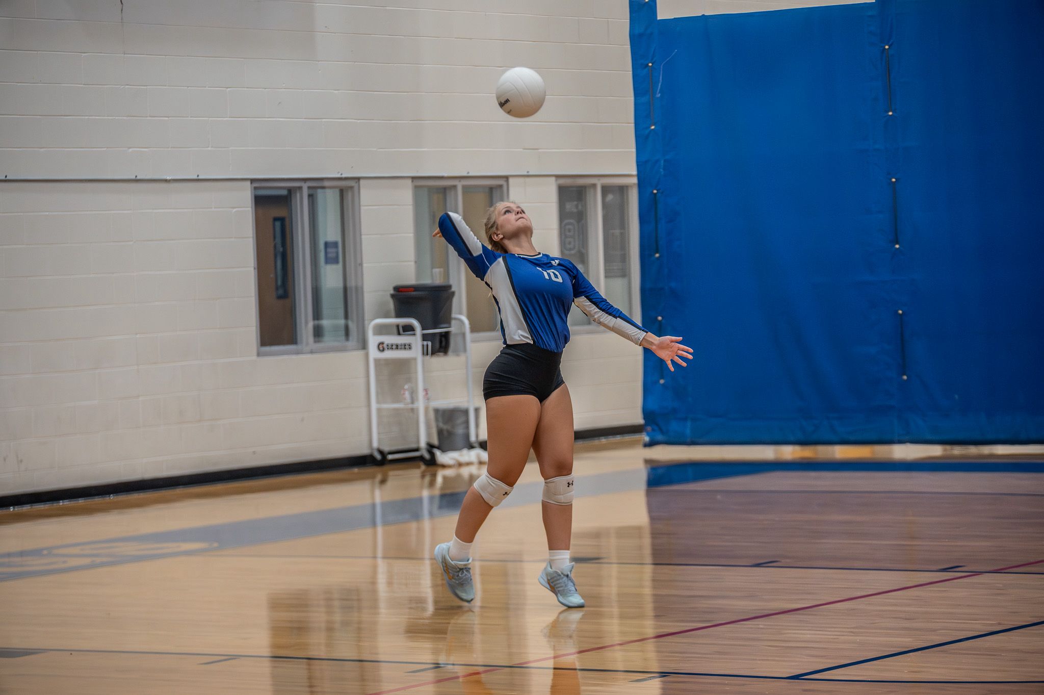 Volleyball player serving in blue jersey